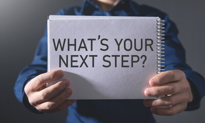 Man showing What's Your Next Step? on notepad.