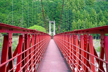Obraz premium 秋葉ダム直下の天竜川に架かる赤い吊り橋 竜山橋（静岡県浜松市）