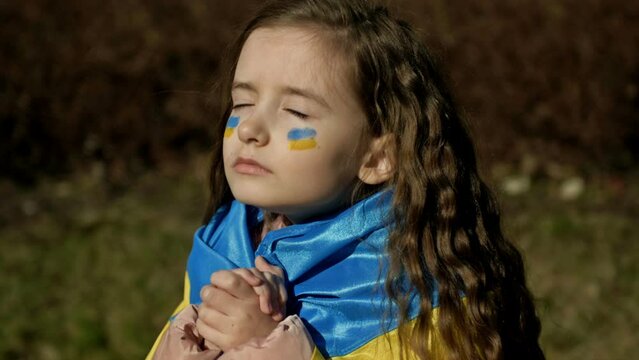 Portrait of a little praying Ukrainian girl. The children are asking for peace.