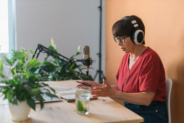 Middle-aged female radio presenter talking into the microphone and reading news - radio broadcast...