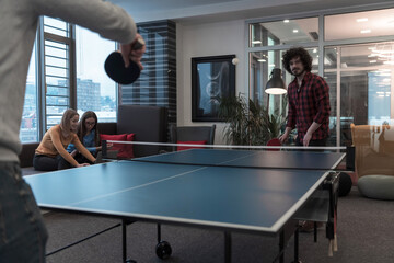 Two young start up business man playing ping pong tennis at modern creative office space people...