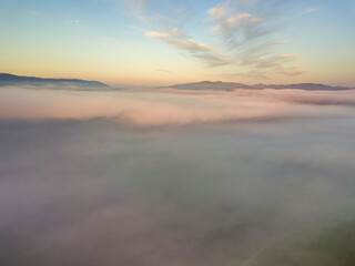 Obraz premium The rays of dawn over the fog in the Ukrainian Carpathians. Aerial drone view.
