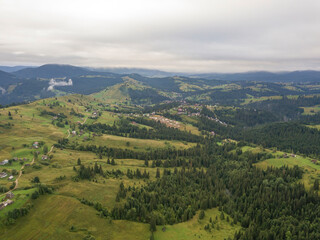 Green slopes of Ukrainian Carpathian mountains in summer. Cloudy morning, low clouds. Aerial drone view.