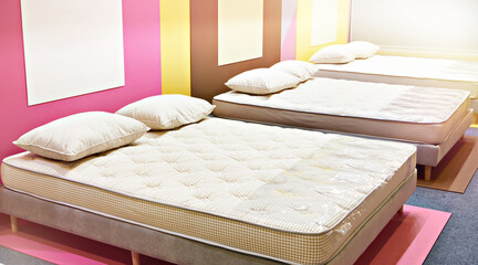 Modern bed with mattresses and pillows in store