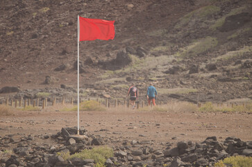 Red no bathing flag and two men walking in the background. El Confital. La Isleta. Las Palmas de...