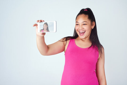 Make your day as awesome as your selfie. Studio shot of a cute young girl taking a selfie with a mobile phone against a gray background.