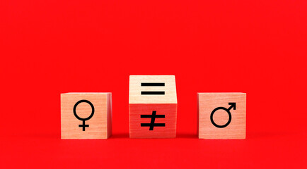Gender signs on wooden cubes and signs of equality and inequality on a red background. Gender...