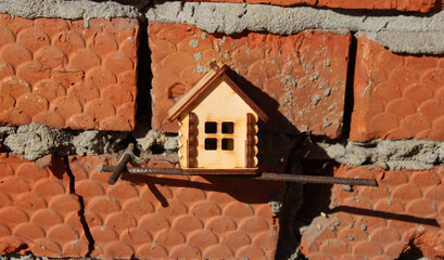 Small wooden house against the background of a red brick defective wall