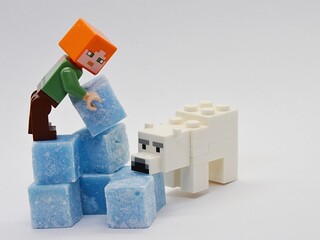 Obraz premium LEGO Minecraft Alex is building igloo from ice looking light blue scented stearine wax cubes, Minecraft polar bear is sniffing one of the cubes.