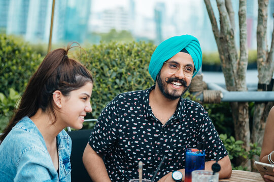 Friends Talking and Laughing in the Outdoor Cafe.
Indian group of friends sitting together in a cafe and drinking cocktails.