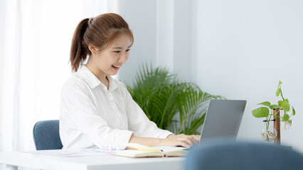 A beautiful Asian businesswoman sitting in her private office, she is checking company financial documents, she is a female executive of a startup company. Concept of financial management.