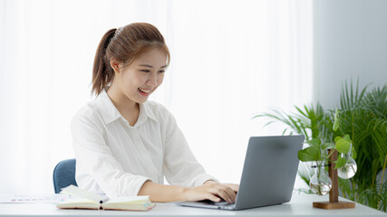 A beautiful Asian businesswoman sitting in her private office, she is checking company financial documents, she is a female executive of a startup company. Concept of financial management.