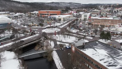 Drone flying over Viskan river in snowy Boras city, Sweden. Aerial forward tlt up reveal