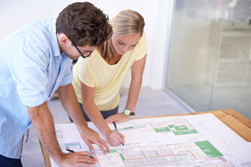 Planning out the fine details. Two architects discussing elements of an architectural plan.