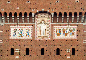 Fragment of facade of castle with statue of St. Ambrose and coats of arms of Sforza family in...