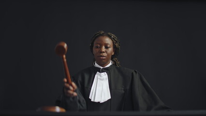 Serious black female judge hitting gavel, calling to stand court members, making announcement