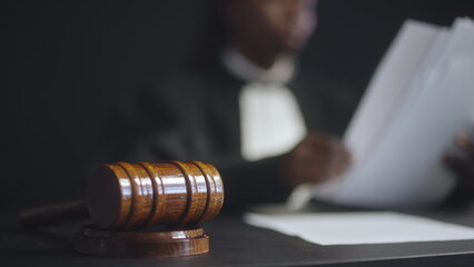 Female judge working with papers in court room, gavel on table, justice symbol