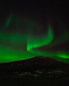 Beautiful northern lights dancing over the top of a mountain in Norwa