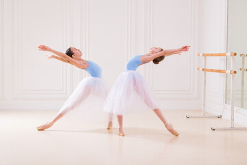 Young ballerinas having rehearsal at studio. Row of happy young ballerinas practicing at ballet barre, focus on first girl.