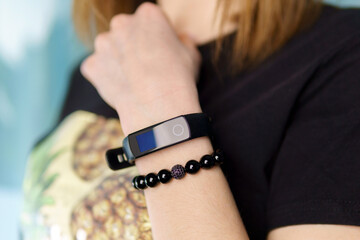 The decoration is a black agate bracelet and a fitness bracelet on the arm. Natural stone jewelry.
