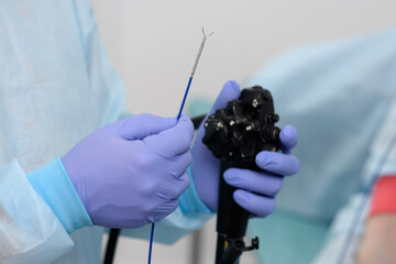 Instruments for gastroscopy close-up. The doctor holds in his hands a flexible endoscope and...