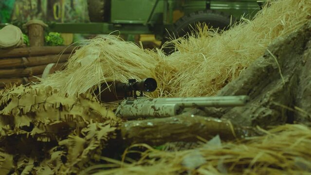 4k Close up view of sniper dressed in ghillie suit or grass cloak waiting and looking by rifle optics . Sharpshooter aims and shoots . Sharp shooter shooting . Shot on ARRI movie camera in Slow Motion