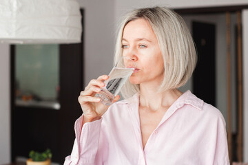 adult woman holding glass of pure mineral water at home