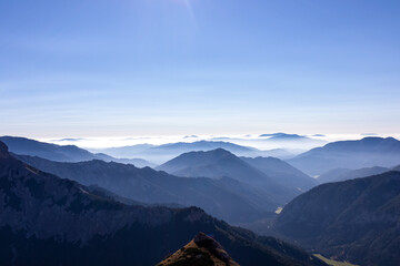 A panoramic view on the mountain peaks of the Hochschwab Region in Upper Styria, Austria. Cloudless weather on a sunny summer day in the Alps. Blue misty valley and soft hills. Concept freedom
