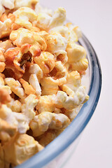 Big transparent glass bowl of freshly popped popcorn on white background