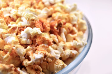 Big transparent glass bowl of freshly popped popcorn on white background