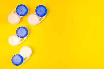 Medical containers for eye lenses on a yellow background