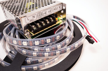 Plastic coil with a led light-emitting diode tape in a silicone shell with a transformer on a white...