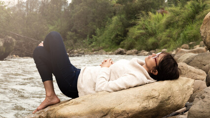 woman resting on a rock next to a river in boyaca colombia