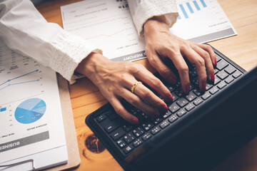 Business woman reviewing data in financial charts and graphs on wooden desk in office and business working, tax, accounting, statistics and analytic research concept