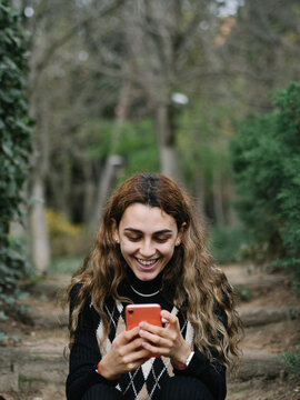 mujer joven sonriendo y siendo feliz con su tel&eacute;fono m&oacute;vil 