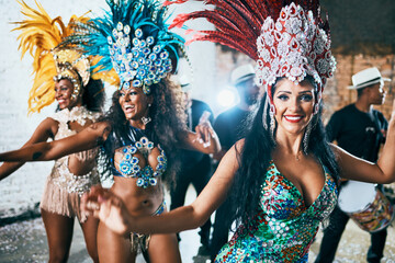 We are here to entertain you. Cropped shot of beautiful samba dancers performing in a carnival with...