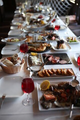 Served  holiday table with different food. Banquet for many people, snacks before the celebration. Glasses of wine, bread, meat, lemon, salmon, oysters,
