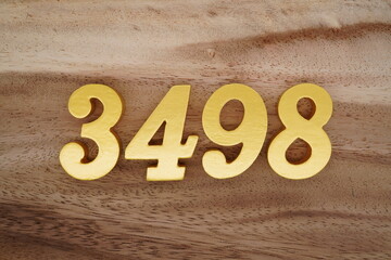 Golden Arabic numerals on a real brown and white wooden floor number 3498
