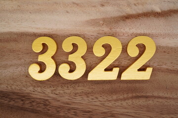 Golden Arabic numerals on a real brown and white wooden floor number 3322