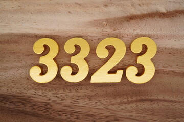 Golden Arabic numerals on a real brown and white wooden floor number 3323