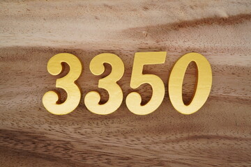 Golden Arabic numerals on a real brown and white wooden floor number 3350