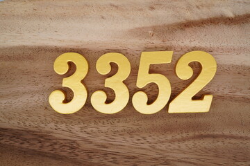 Golden Arabic numerals on a real brown and white wooden floor number 3352