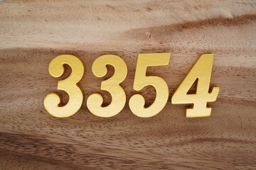 Golden Arabic numerals on a real brown and white wooden floor number 3354