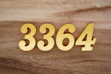 Golden Arabic numerals on a real brown and white wooden floor number 3364