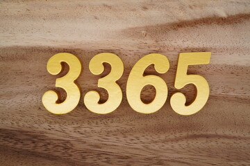Golden Arabic numerals on a real brown and white wooden floor number 3365