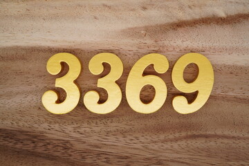 Golden Arabic numerals on a real brown and white wooden floor number 3369