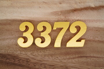 Golden Arabic numerals on a real brown and white wooden floor number 3372
