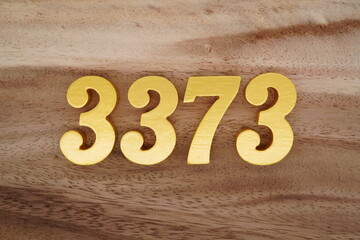 Golden Arabic numerals on a real brown and white wooden floor number 3373