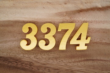 Golden Arabic numerals on a real brown and white wooden floor number 3374