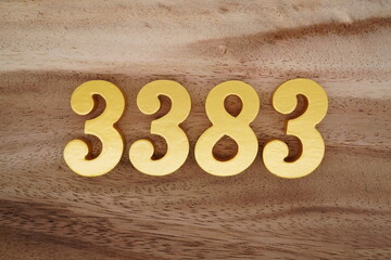 Golden Arabic numerals on a real brown and white wooden floor number 3383